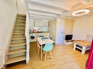 Une cuisine compacte avec un coin repas, un lave-linge et un téléviseur.