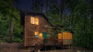 A cabin with a wooden exterior, a deck, and a sign indicating it is a lodge. - Unicoi Pines | Hot Tub, Pet-Friendly Cabin Near Helen, GA (Sautee Nacoochee)