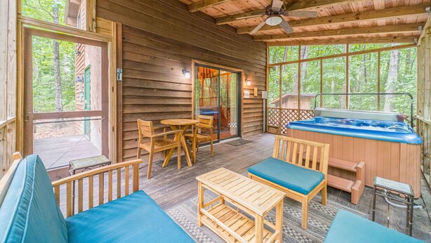 A wooden cabin with a hot tub, wooden furniture, and large windows. - Unicoi Pines | Hot Tub, Pet-Friendly Cabin Near Helen, GA (Sautee Nacoochee)