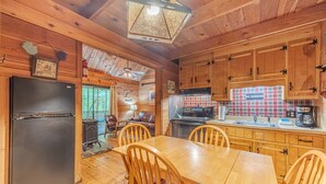 A wooden cabin interior with a dining table, chairs, a refrigerator, a stove, and a 'No Smoking' sign. - Unicoi Pines | Hot Tub, Pet-Friendly Cabin Near Helen, GA (Sautee Nacoochee)