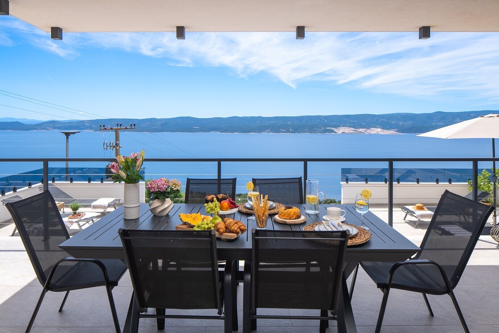 A table set for breakfast with a view of the sea and mountains.