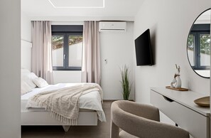 A modern bedroom with a bed, bedside table, chair, TV, and a large window with curtains. - Seaview Villa EBS, Your Mediterranean Retreat (Lokva Rogoznica)