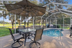 A covered patio area with a glass table and chairs, a pool, and a view of a golf course. - 2/2.5 Pool Home on Golf Course in Village of La Reynalda (The Villages)