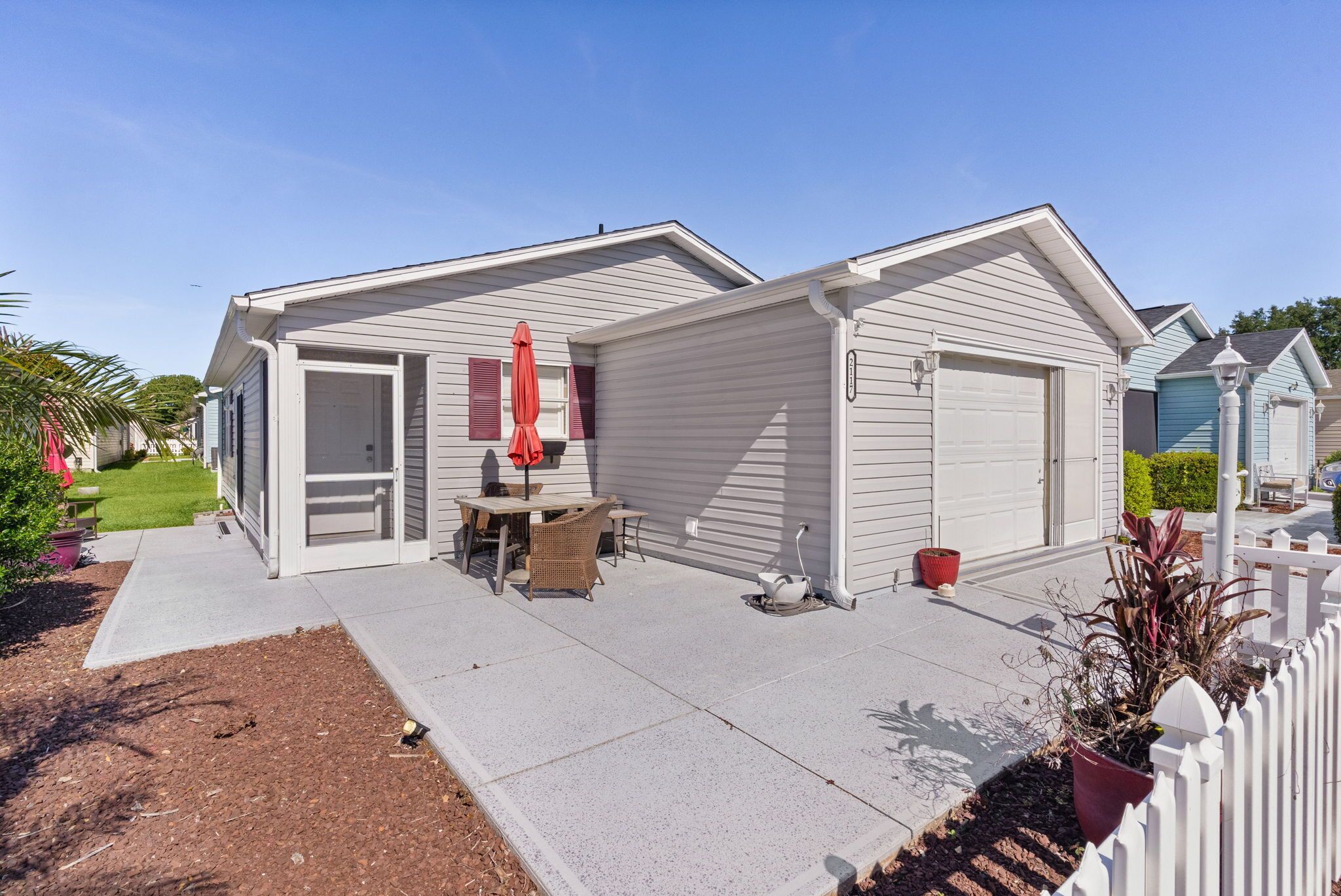 A single-story house with a garage, a patio with outdoor furniture, and a small garden area.