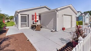 Uma casa térrea com garagem, um pátio com móveis de exterior e um pequeno jardim.