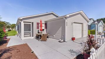 A single-story house with a garage, a patio with outdoor furniture, and a small garden area.