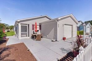 Einbungalow mit Garage, einer Terrasse mit Gartenmöbeln und einem kleinen Garten.