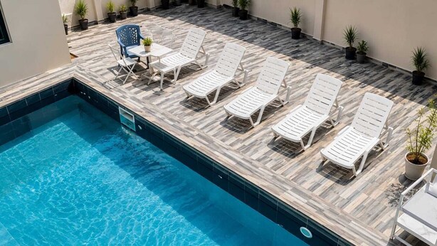 Una piscina con lettini e piante in vaso.