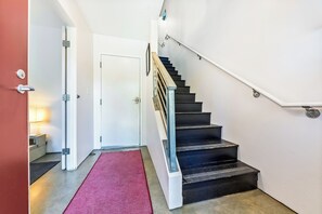 Un escalier recouvert d’un tapis rouge menant à une porte blanche.