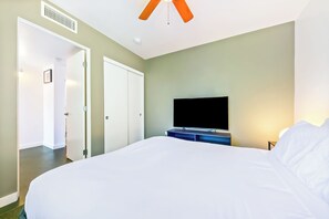 A hotel room with a large bed, a flat-screen TV, a ceiling fan, and a door leading to another room. - Heart Of North Park, Mins To Beach & Restaurants (San Diego)