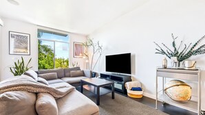 Uma sala de estar moderna com sofá, mesa de centro, televisão e objetos decorativos.