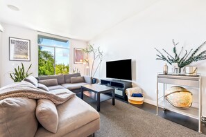 A modern living room with a sofa, coffee table, TV, and decorative items. - Heart Of North Park, Mins To Beach & Restaurants (San Diego)