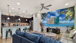 A modern kitchen with dark cabinets, a central island, and a dining area with bar stools. - Fun Family Townhome with Private Pool & Game Room! (Kissimmee)