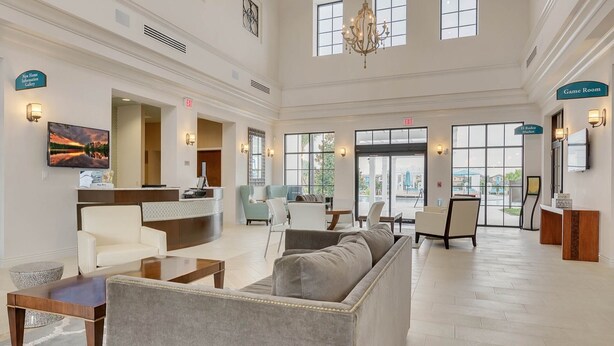 A spacious lobby with a reception desk, seating area, and large windows offering views of the outside. - Fun Family Townhome with Private Pool & Game Room! (Kissimmee)