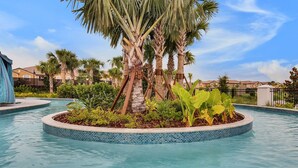 A swimming pool with a tiled edge, surrounded by palm trees and tropical plants. - Fun Family Townhome with Private Pool & Game Room! (Kissimmee)