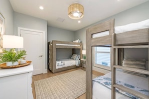A bedroom with bunk beds, a bedside table, a lamp, a plant, and a window with blinds. - Bayfront Retreat 5-min to Vanderbilt Beach (Naples)
