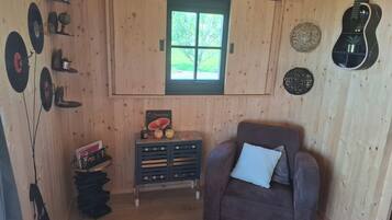 Een houten interieur met een raam, een gitaar, een bank en een bijzettafeltje met decoratieve objecten.