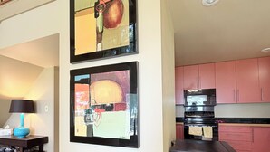 A modern kitchen with stainless steel appliances, a dining area with a glass table, and two abstract paintings on the wall. - Pendleton Paradise Waterfront Cabin on Lanan Bay (Zwolle)