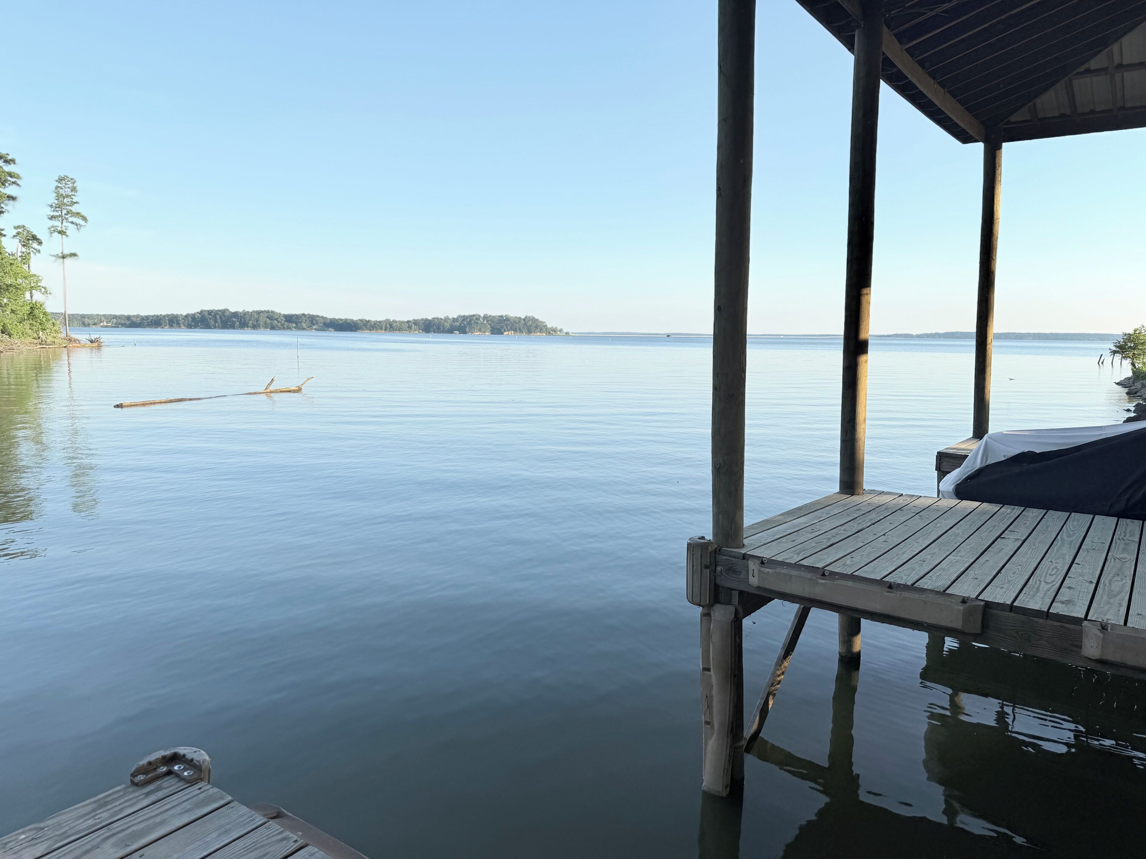 A wooden dock extending over calm water with a clear sky.