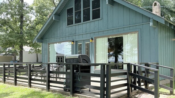 A rustic wooden building with a porch, a chimney, and a fenced area. - Pendleton Paradise Waterfront Cabin on Lanan Bay (Zwolle)