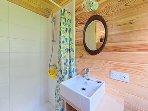 Un bagno con doccia, lavandino, specchio e rivestimenti in legno.
