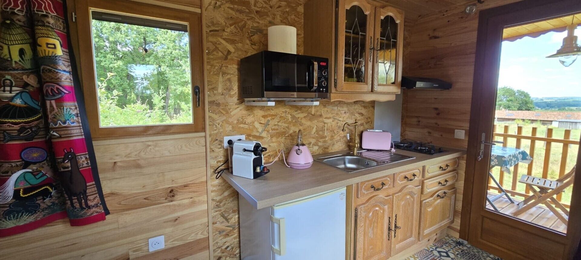 A compact kitchen with a microwave, toaster, sink, and wooden cabinets.