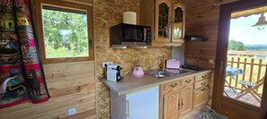 Una cocina compacta con microondas, tostadora, fregadero y armarios de madera.