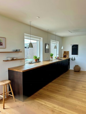 A modern kitchen with a wooden island, pendant lights, and a blackboard on the wall. - Wake up to views of Kattegat and Samsø (Norsminde)