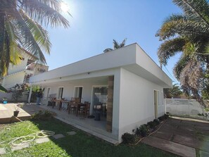 Une maison moderne à deux étages, dotée d’un patio couvert, d’un escalier et d’un jardin.