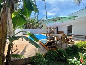 Un espace piscine doté d’une terrasse en bois, de chaises longues et d’une table avec des chaises.