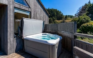 A hot tub on a wooden deck adjacent to a building with a window. - Love Nest | Ocean View Cottage & Hot Tub (Sea Ranch)