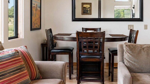 A dining area with a wooden table, chairs, and a pendant light. - Love Nest | Ocean View Cottage & Hot Tub (Sea Ranch)