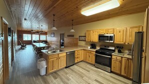 A kitchen with wooden cabinets, a stainless steel refrigerator, a microwave, and a stove. - Cass Lake Lodge (Cass Lake)