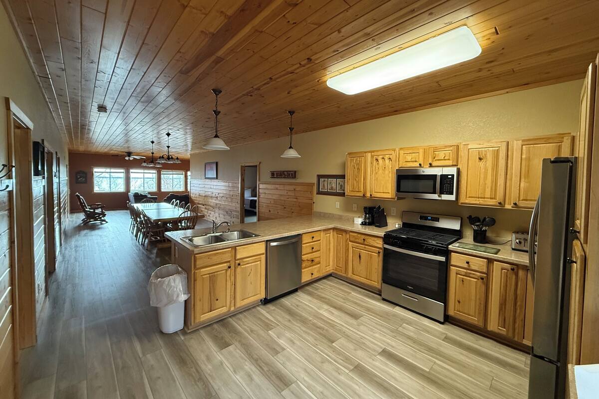 A kitchen with wooden cabinets, a stainless steel refrigerator, a microwave, and a stove.