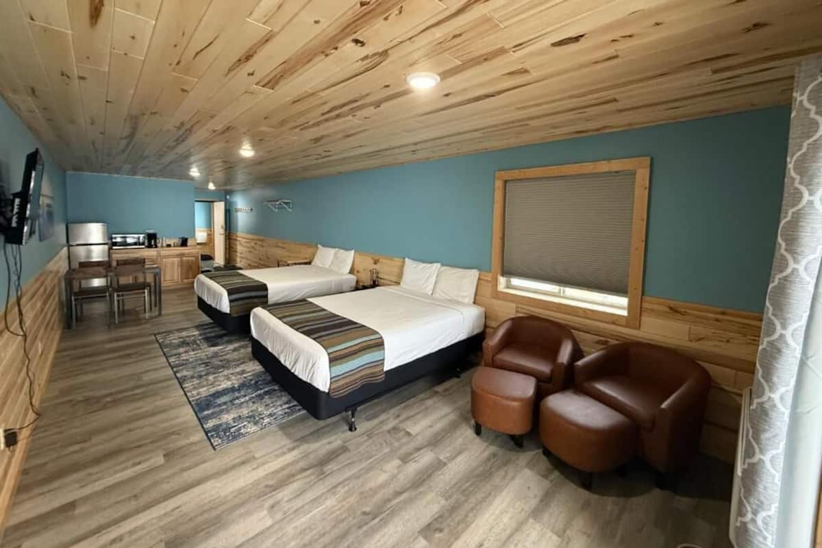A room with two beds, a desk, a chair, and a window.