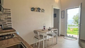 A kitchen with a sink, stove, and dining area with chairs and a table. - Nice apartment in villa for 2 guests with WIFI, TV, balcony and pets allowed (Finale Ligure)