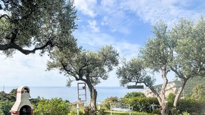 A garden with a stone bench, a metal bench, and a white signboard. - Nice apartment in villa for 2 guests with WIFI, TV, balcony and pets allowed (Finale Ligure)