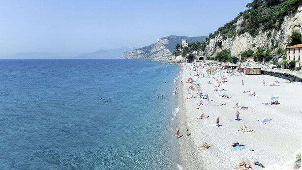 A beach with clear blue water, a rocky cliff, and a building on top. - Nice apartment in villa for 2 guests with WIFI, TV, balcony and pets allowed (Finale Ligure)