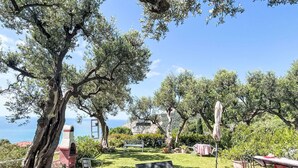 Un jardin doté d’un espace extérieur aménagé pour s’asseoir, offrant une vue sur la mer et comprenant une structure en pierre.