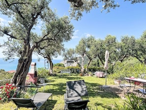 Un giardino con posti a sedere all'aperto, vista sul mare e una costruzione in pietra.