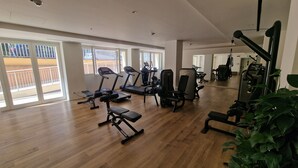 A spacious gym with treadmills, weight machines, and a mirror. Large windows provide natural light, and a balcony is visible outside. - Domus Aventinae relax & fit (Roma)