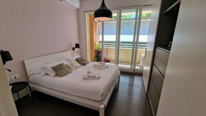 A bedroom with a bed, bedside tables, a lamp, a sliding glass door to a balcony, and a TV. - Domus Aventinae relax & fit (Roma)