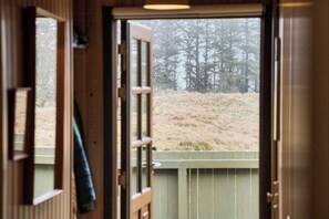 A wooden door with a view of a grassy field and trees. - Holiday home in coastal nature with turf roof (Løkken)