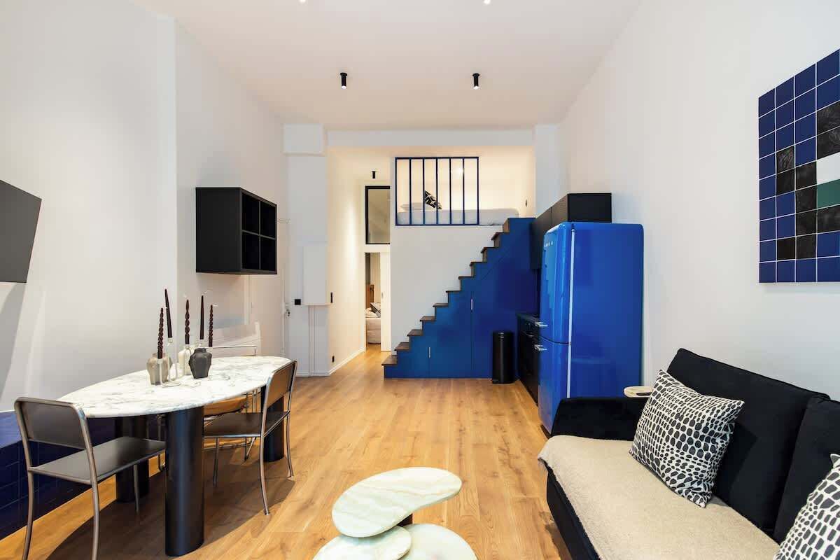 A modern interior with a dining area, a sofa, and a staircase.