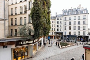 Eine Straßenszene mit einem Gebäude, das einen Laden namens 'LE MAGASIN ASPHALTE' und einen weiteren namens 'FREDBION' zeigt.