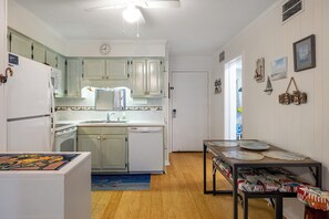 A compact kitchen with white cabinets, a refrigerator, a dishwasher, and a dining area with a table set for two. - Southwinds A9 - 2 Bedrooms, 1.5 Baths, Oceanfront Condo (Atlantic Beach)