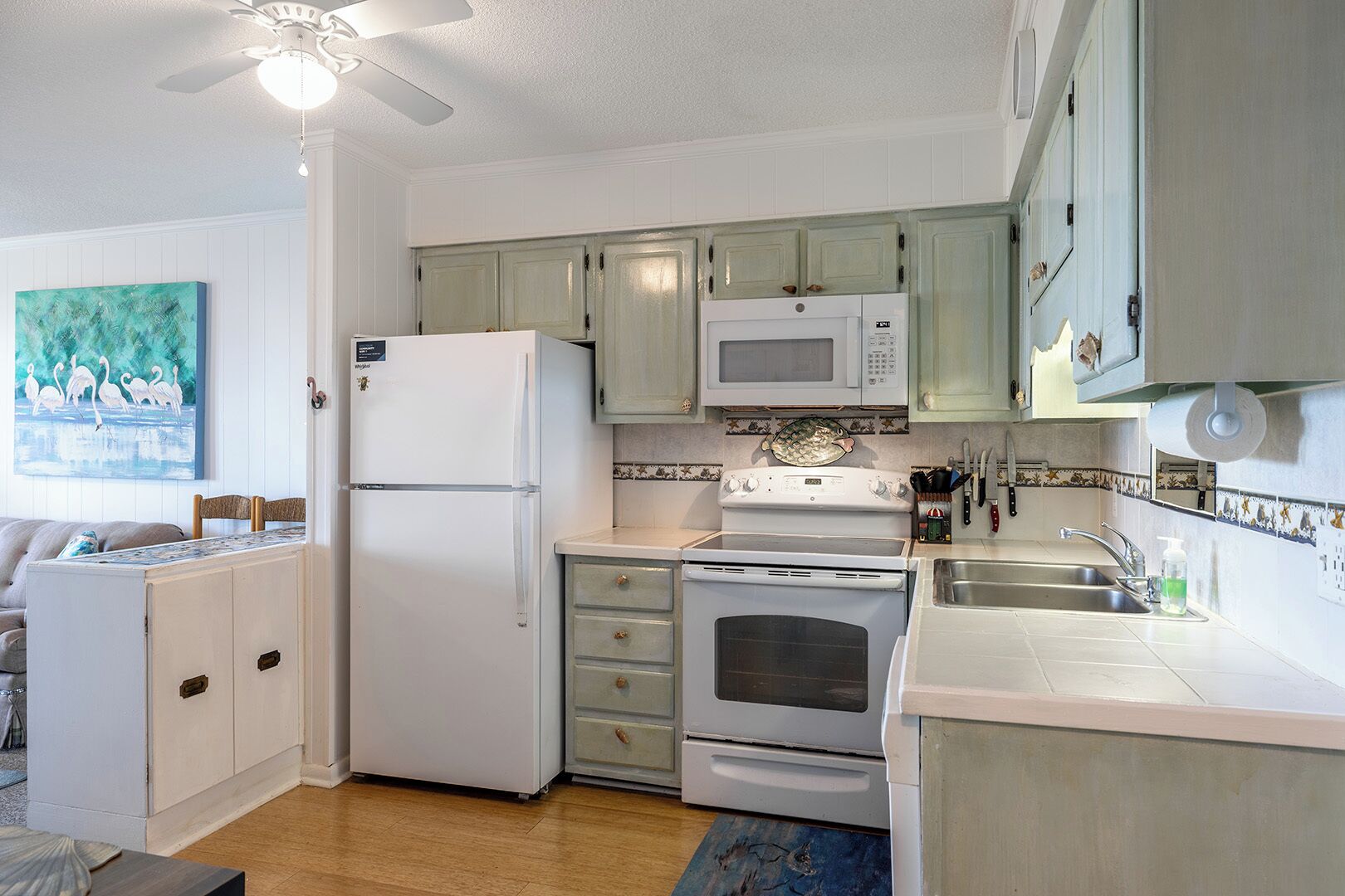A compact kitchen with a refrigerator, microwave, stove, and sink.