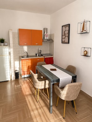 Une cuisine compacte avec des meubles de couleur orange, un évier en acier inoxydable et un petit plan de travail.