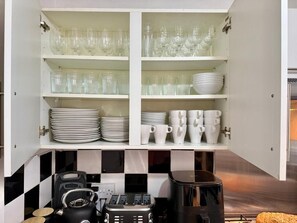 Un meuble de cuisine contenant de la verrerie, des assiettes et des tasses.
