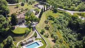 Luftaufnahme eines Anwesens mit Schwimmbad, Steinhaus und angelegtem Garten.